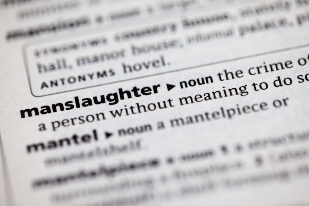 A close-up view of a dictionary page, with the word "manslaughter" and its definition in sharp focus.