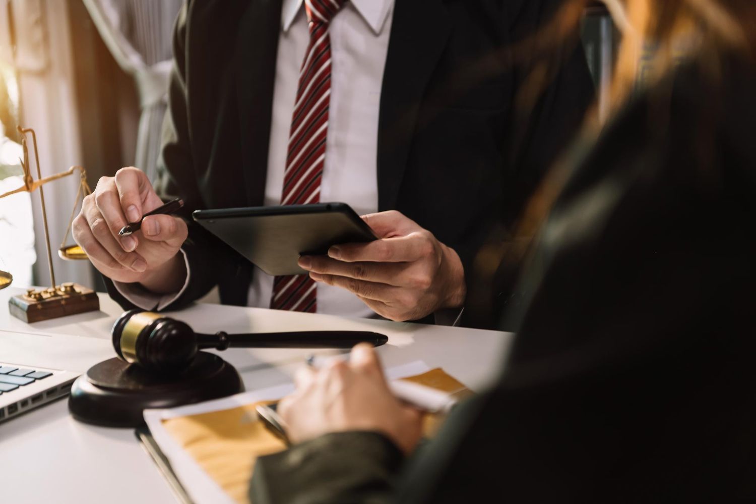 Two legal professionals review a tablet and documents