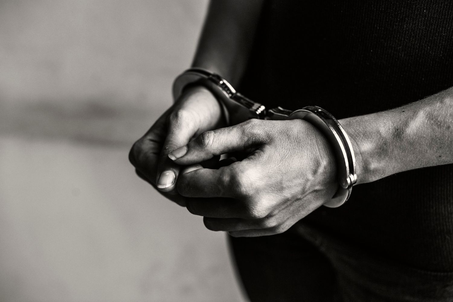 A black and white image displays hands clasped together
